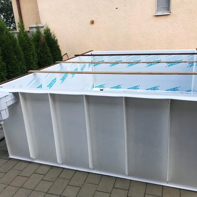 Na plastovom bazéne je umiestnená konštrukcia z dreva, ktorá je určená na jeho prepravu.